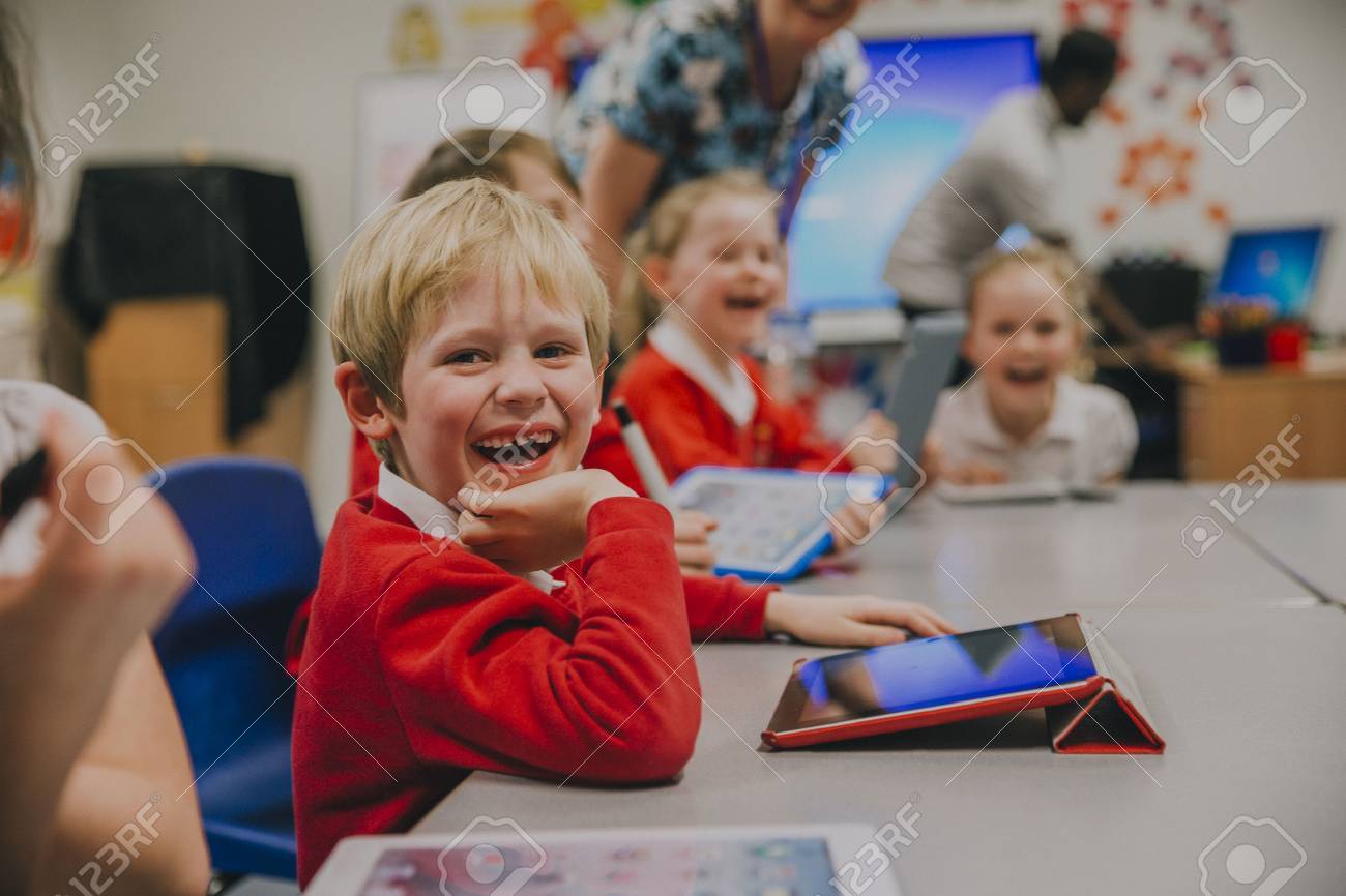 Happy little boy is smiling for the camera while using a digital tablet in his technology lesson at school. - 77181058 Happy little boy is smiling for the camera while using a digital tablet in his technology lesson at school. - 77181058
