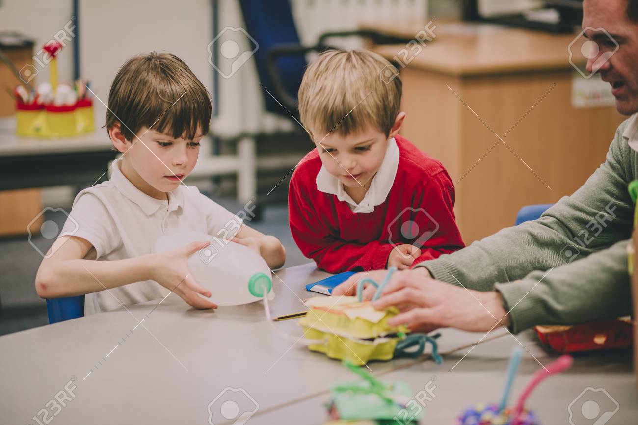 Teacher is helping his primary school students in the classroom with their STEM project. - 77516093 Teacher is helping his primary school students in the classroom with their STEM project. - 77516093