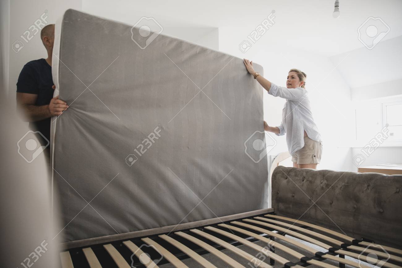 Mature couple are setting up their bed in their new home. - 108206620 Mature couple are setting up their bed in their new home. - 108206620