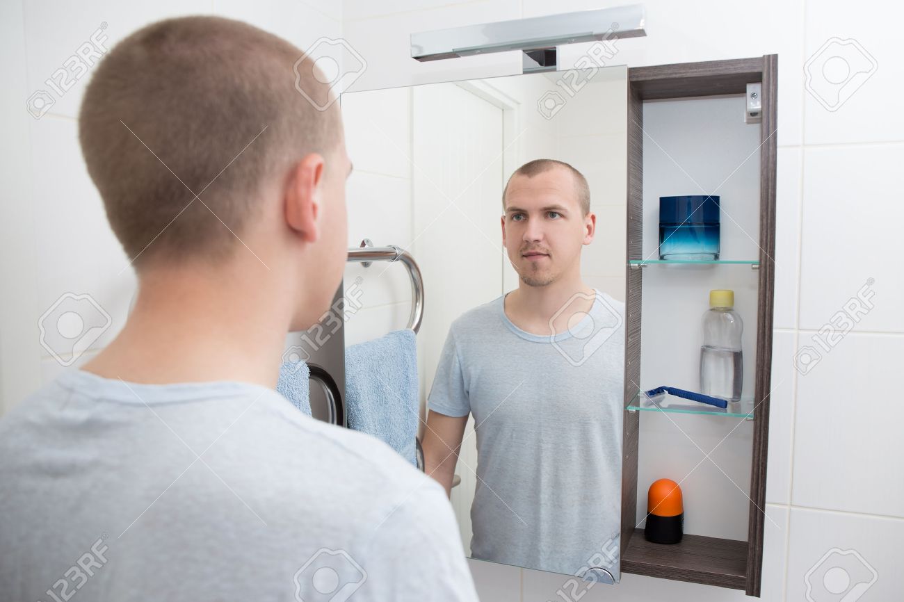 handsome man looking at mirror in bathroom stock photo picture and