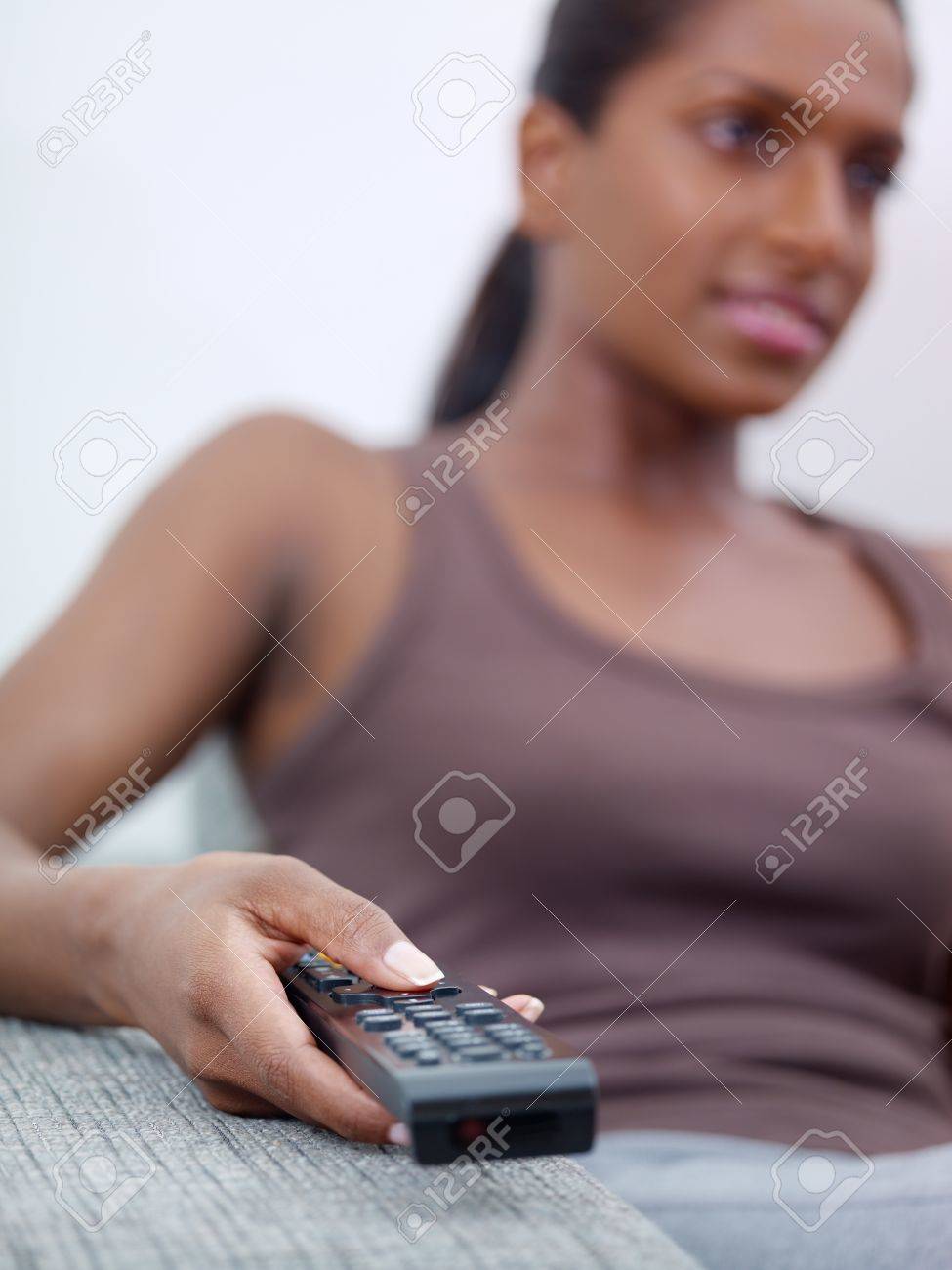 Mid Adult Indian Woman On Sofa, Changing Tv Channel With Remote Control  Stock Photo, Picture and Royalty Free Image. Image 10119207.