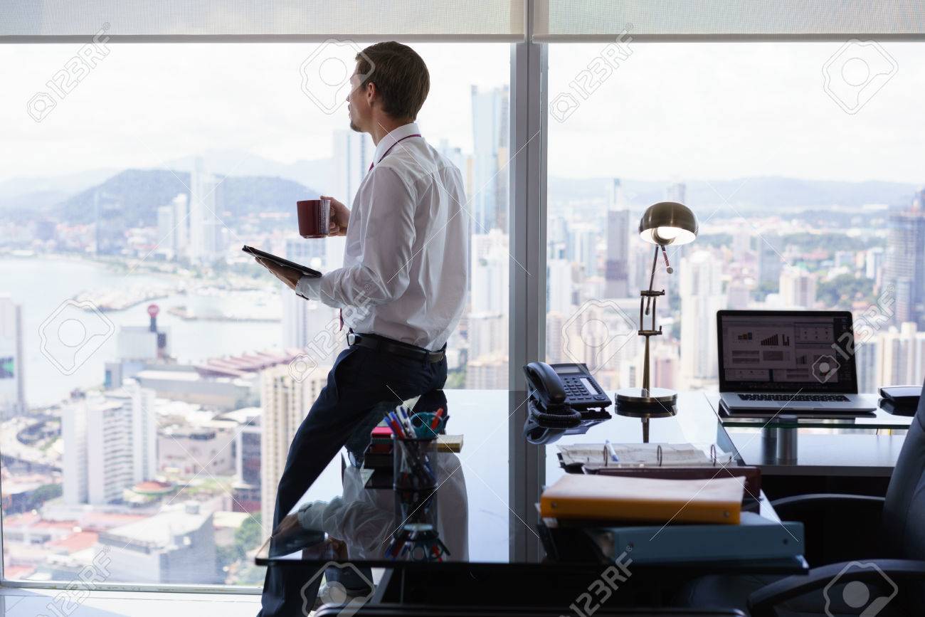 bürogebäude schreibtisch desk erwachsener geschäftsmann auf schreibtisch im modernen büro sitzen und nachrichten mit einer tasse kaffee tablet auf im modernen sitzen bürogebäude schreibtisch desk erwachsener geschäftsmann auf schreibtisch im modernen büro sitzen und nachrichten mit einer tasse kaffee tablet auf im modernen sitzen