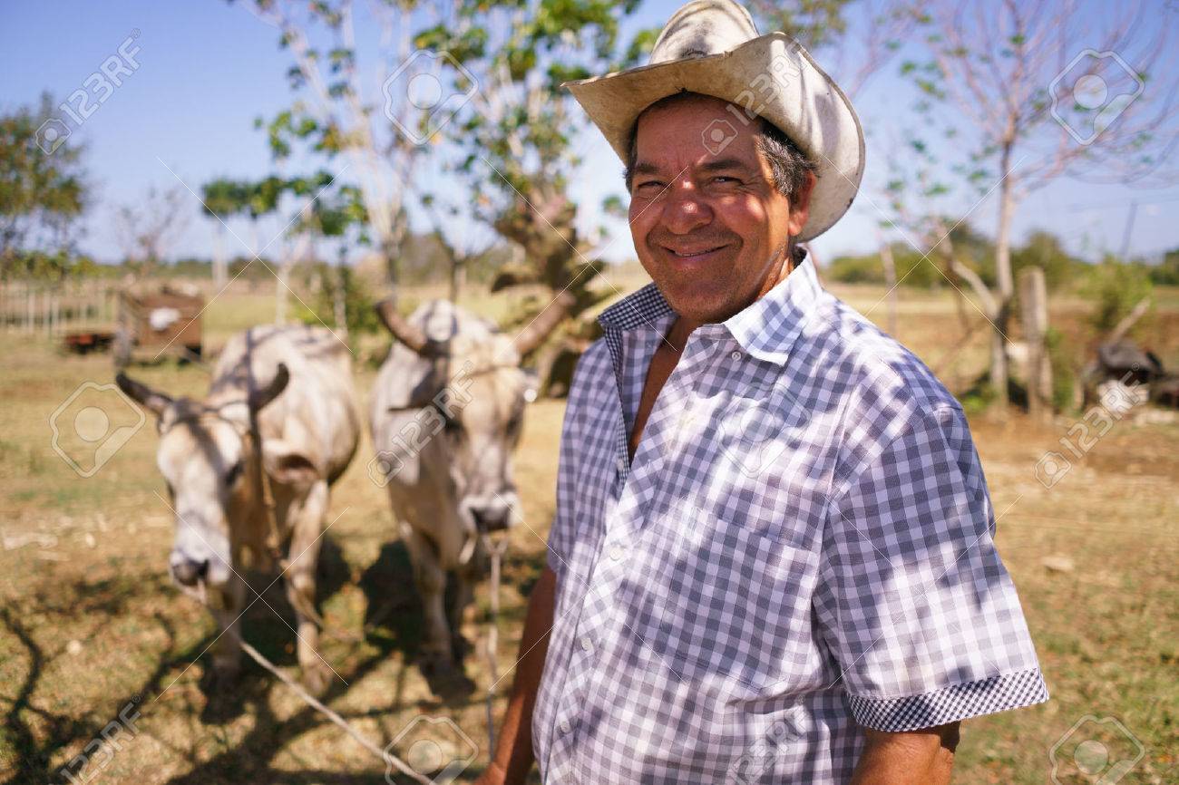 Farming and cultivations in Latin America. Portrait of middle aged hispanic farmer sitting proud in his tractor at sunset, holding the volante. He looks at the camera and smiles happy. - 56140489 Farming and cultivations in Latin America. Portrait of middle aged hispanic farmer sitting proud in his tractor at sunset, holding the volante. He looks at the camera and smiles happy. - 56140489
