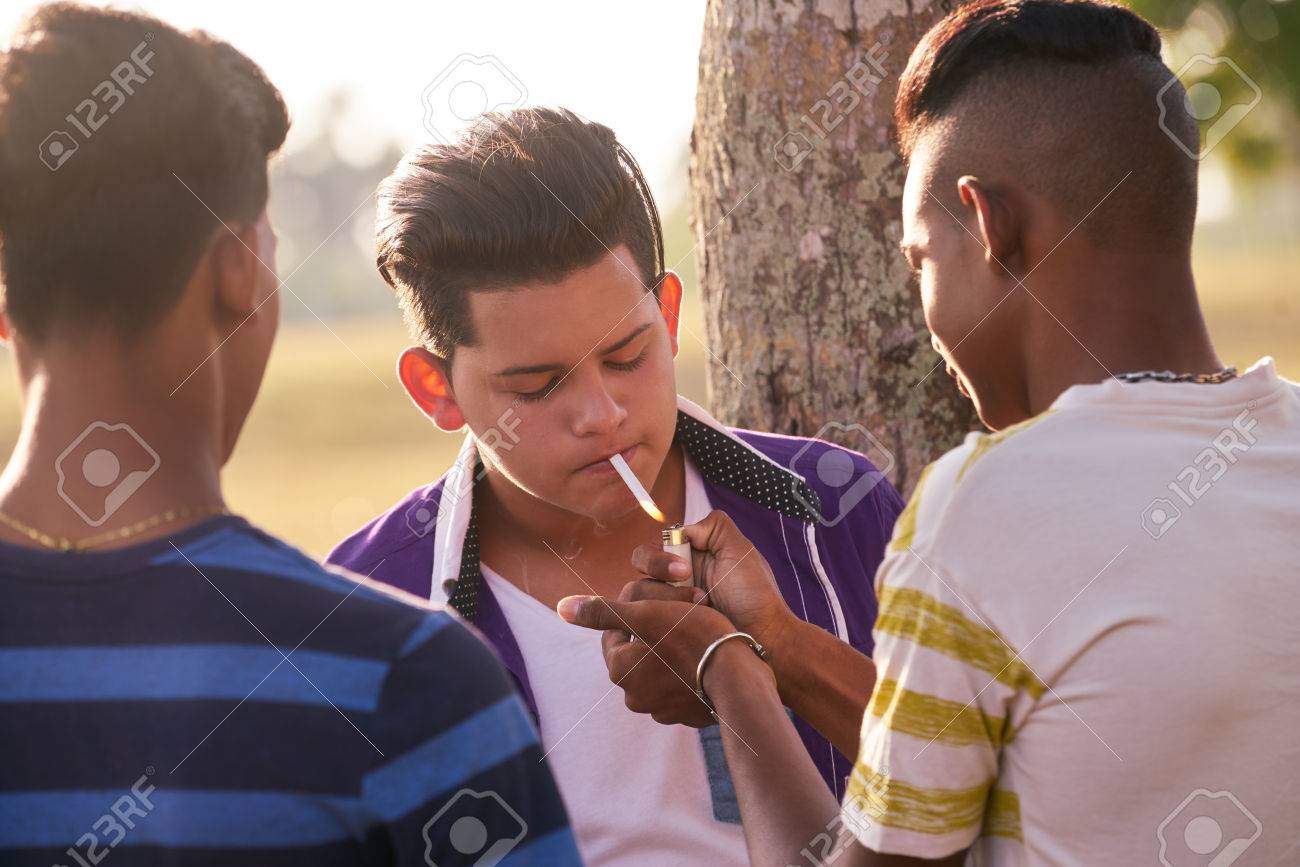 Youth culture, young people, group of male friends, mixed race teen outdoor, teenager in park. Hispanic kid smoking cigarette, confident boy, smoker. Health problems, social issues. - 58547956 Youth culture, young people, group of male friends, mixed race teen outdoor, teenager in park. Hispanic kid smoking cigarette, confident boy, smoker. Health problems, social issues. - 58547956