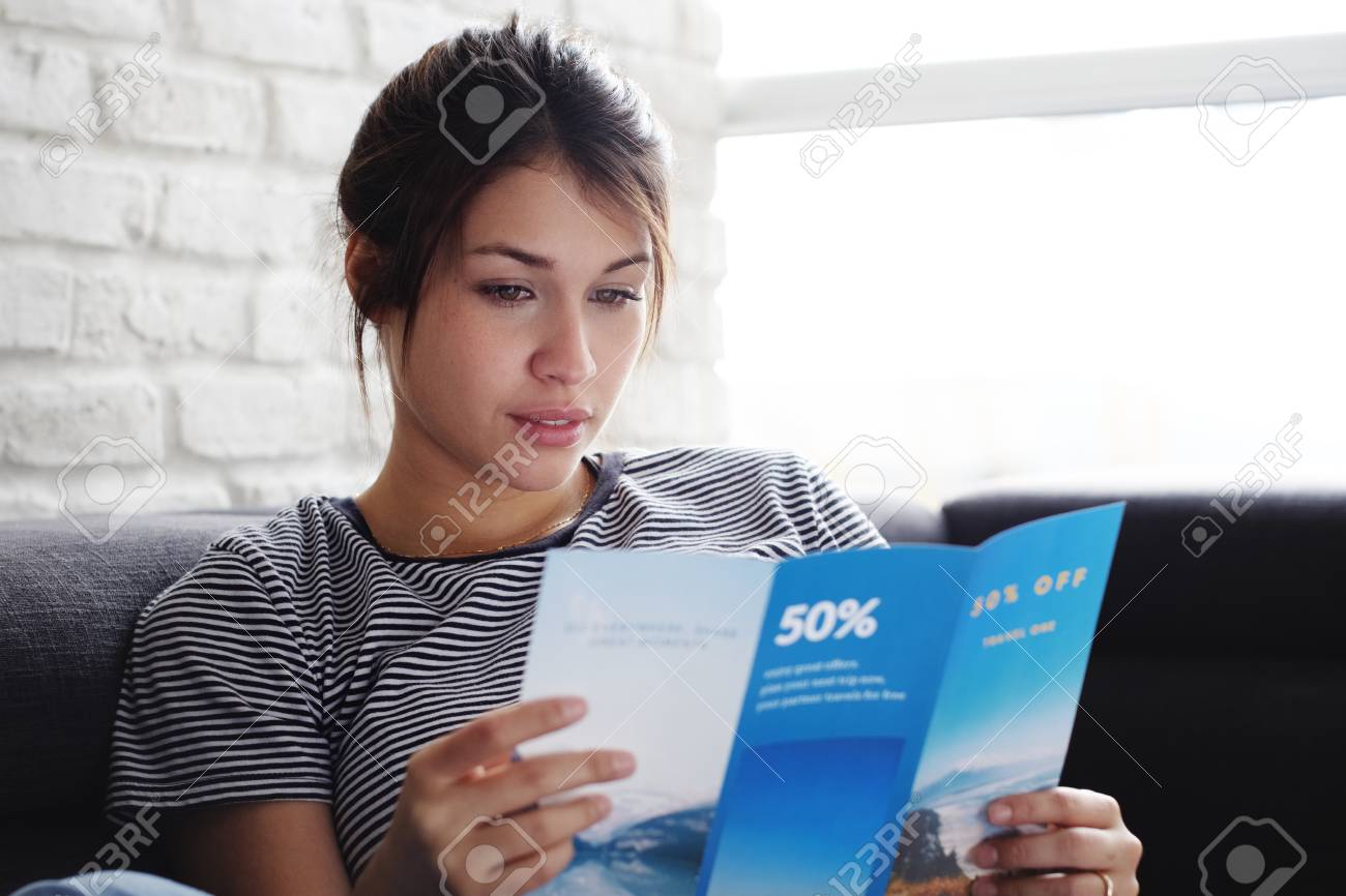 Woman Reading Travel Flye On Sofa At Home - 105913892 Woman Reading Travel Flye On Sofa At Home - 105913892