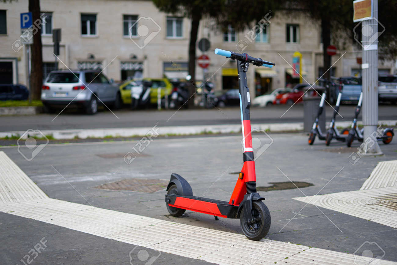 Rental electric scooter parked on the side walk on a rainy day - 167116834 Rental electric scooter parked on the side walk on a rainy day - 167116834