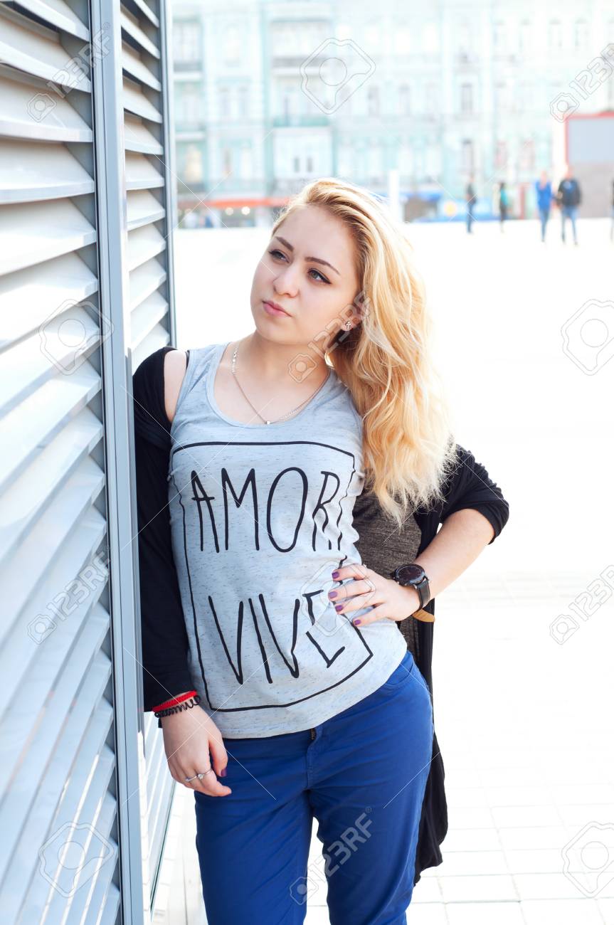 アダルト白人女性ブロンドの髪を着て 青いパンツ T シャツとカーディガン ストリート ファッションを見て の写真素材 画像素材 Image