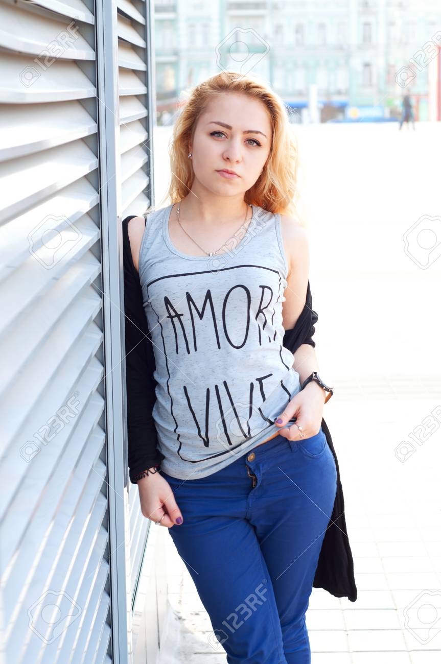 アダルト白人女性ブロンドの髪を着て 青いパンツ T シャツとカーディガン ストリート ファッションを見て の写真素材 画像素材 Image