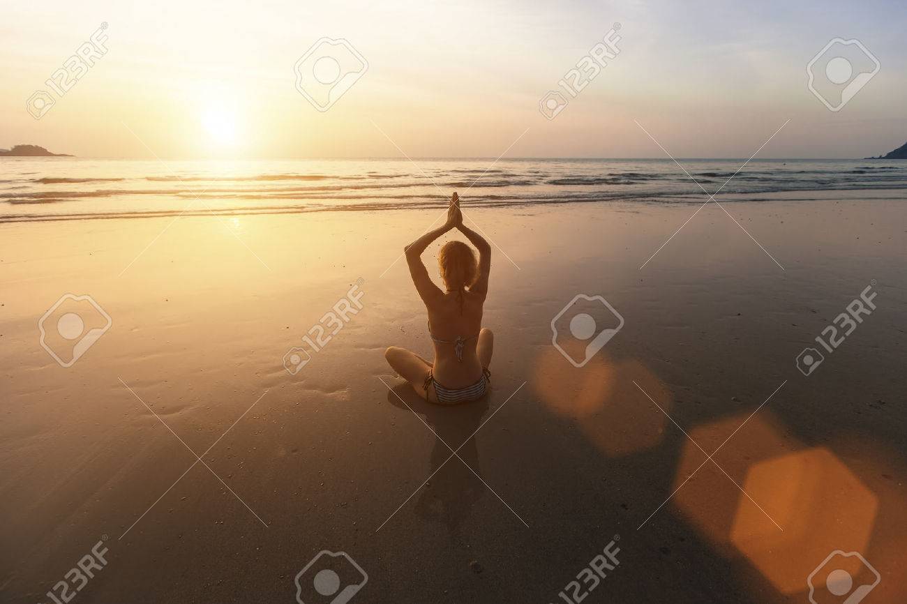 Beautiful girl sitting on the beach during sunset and meditating in yoga pose. - 39950259 Beautiful girl sitting on the beach during sunset and meditating in yoga pose. - 39950259