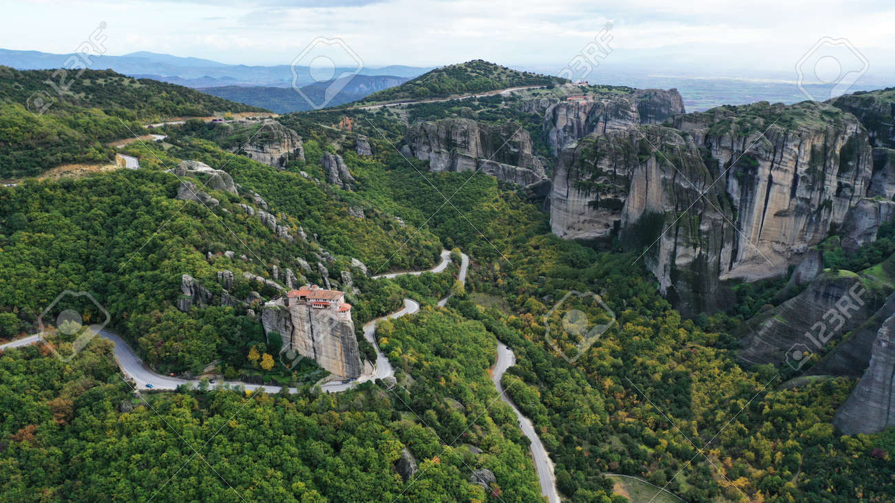 Aerial view of winding road near monastery on the cliff, Meteora mountains valley, Kalampaka, Greece. - 140592755 Aerial view of winding road near monastery on the cliff, Meteora mountains valley, Kalampaka, Greece. - 140592755