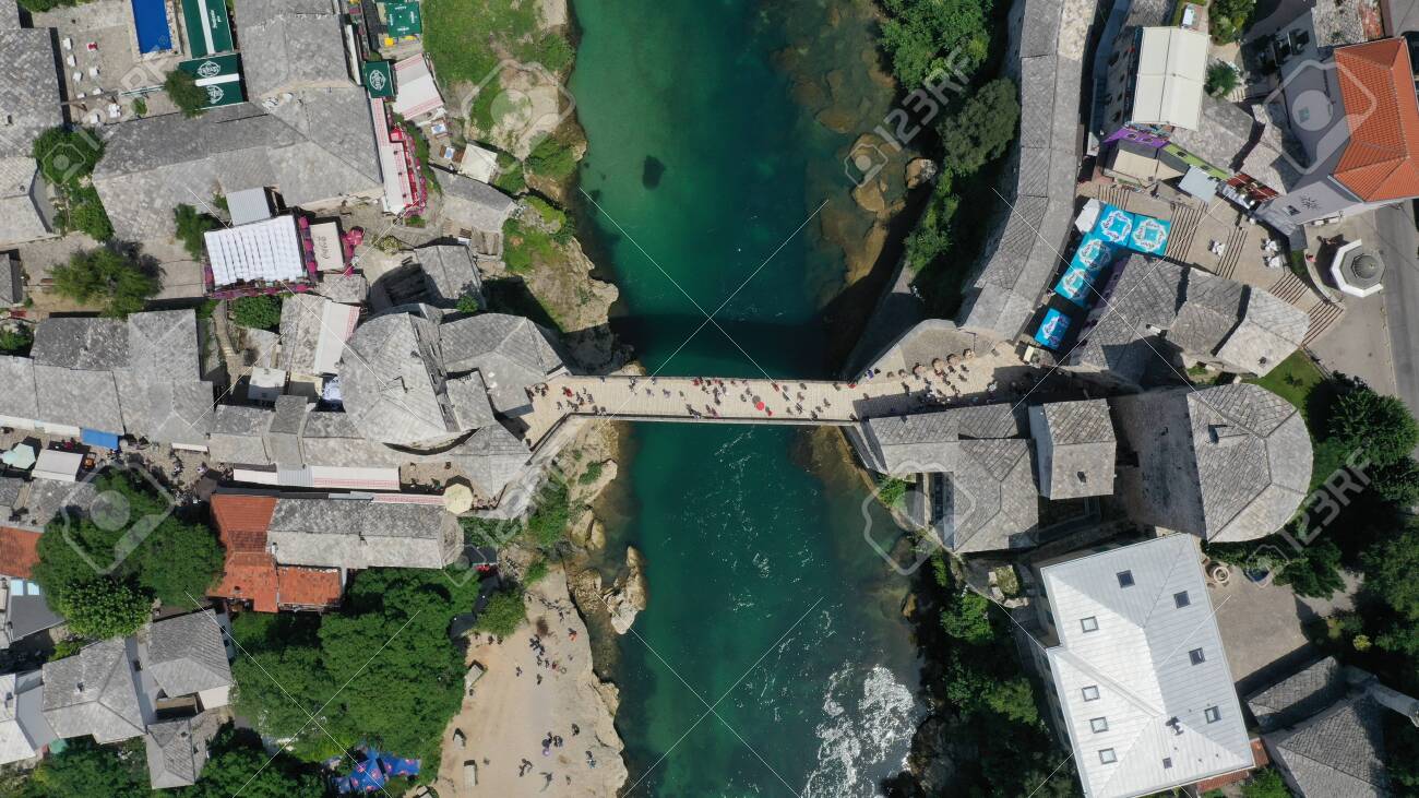 Aerial top down view of old medieval bridge in Mostar, Stari Most, Neretva river, Bosnia and Herzegovina. Sunny summer day. Tourists walking on the bridge. - 139967238 Aerial top down view of old medieval bridge in Mostar, Stari Most, Neretva river, Bosnia and Herzegovina. Sunny summer day. Tourists walking on the bridge. - 139967238