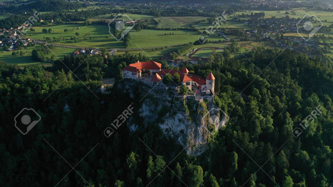 Aerial footage of Bled castle on rocky cliff, Lake Bled in Slovenia, Europe. Natural mountainous landscape around castle, green meadows and fields. Summer. - 141403415 Aerial footage of Bled castle on rocky cliff, Lake Bled in Slovenia, Europe. Natural mountainous landscape around castle, green meadows and fields. Summer. - 141403415