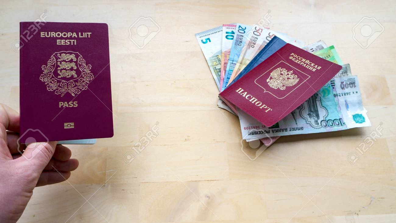 에스토니아, 러시아 또는 유럽 연합 EU 및 러시아 연방 측면 보기 복사 공간 디자인 루블 및 유로 지폐 톤 이미지의 목조 배경 시민권에  여권을 들고 있는 손 로열티 무료 사진, 그림, 이미지