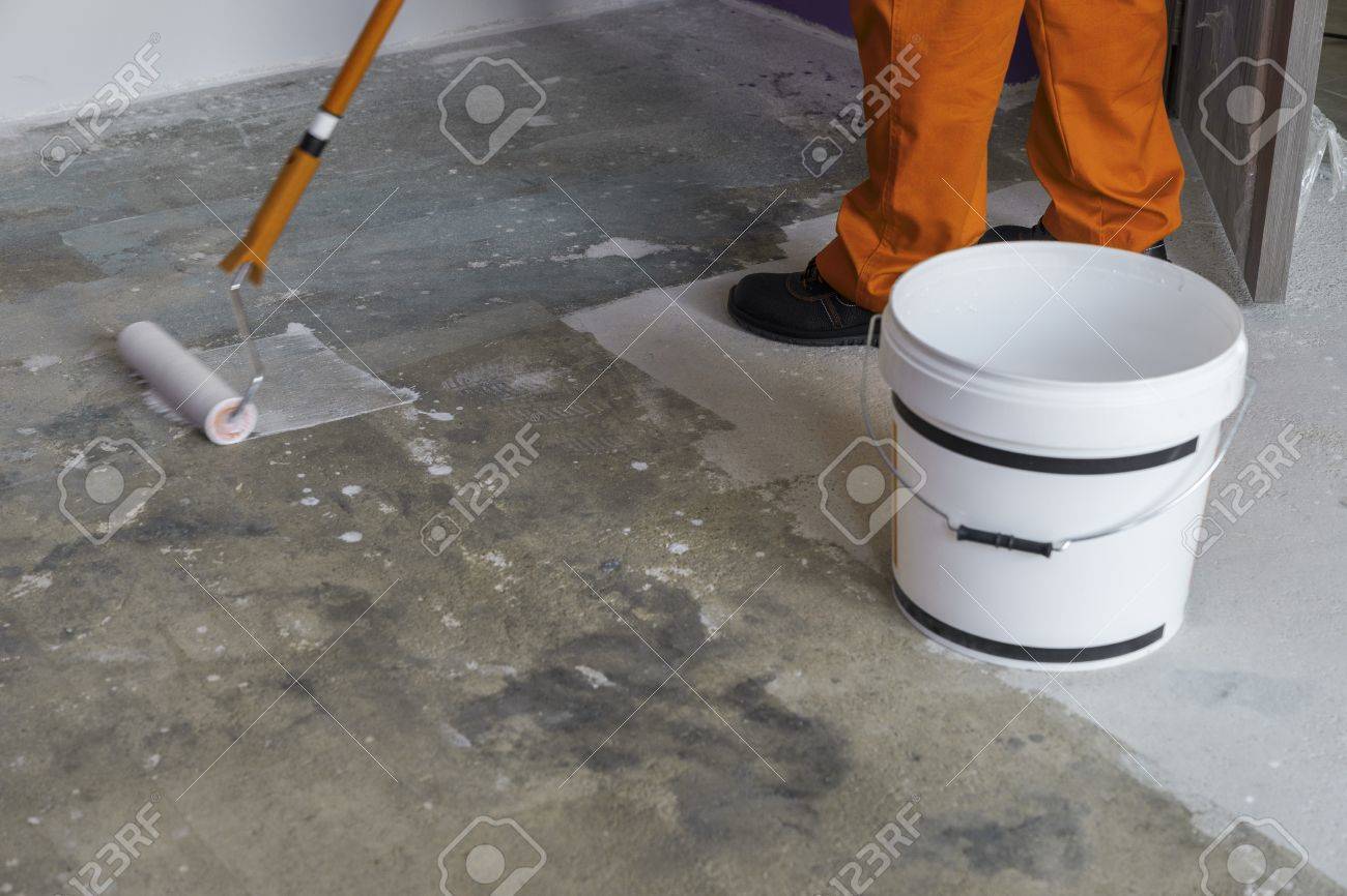 Worker Puts Primer With Roller On Concrete Floor House Under