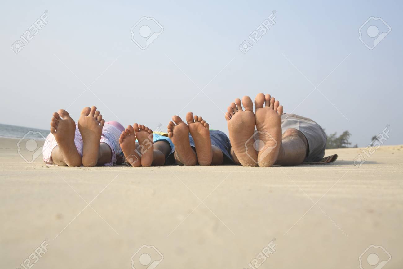 South Asian Indian parent and children showing barefoot sleeping on seashore facing sky - 85731660 South Asian Indian parent and children showing barefoot sleeping on seashore facing sky - 85731660