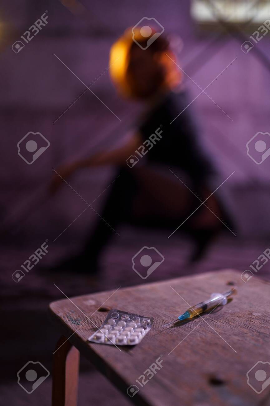 Filled Syringe and Pills on a table - Underground nightclub party dancing of drug addiction redhead caucasian white young woman wearing black sweater, skirt and chocker - Pills and tablets - 122005316 Filled Syringe and Pills on a table - Underground nightclub party dancing of drug addiction redhead caucasian white young woman wearing black sweater, skirt and chocker - Pills and tablets - 122005316