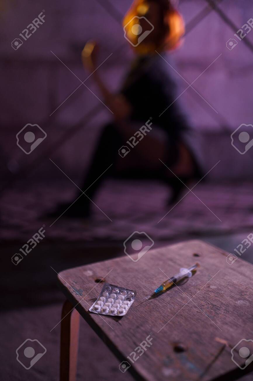 Filled Syringe and Pills on a table - Underground nightclub party dancing of drug addiction redhead caucasian white young woman wearing black sweater, skirt and chocker - Pills and tablets - 122005325 Filled Syringe and Pills on a table - Underground nightclub party dancing of drug addiction redhead caucasian white young woman wearing black sweater, skirt and chocker - Pills and tablets - 122005325