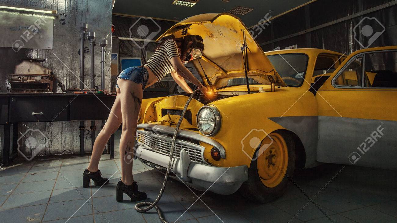 Sexy woman is welding something inside an old car. - 61739098 Sexy woman is welding something inside an old car. - 61739098