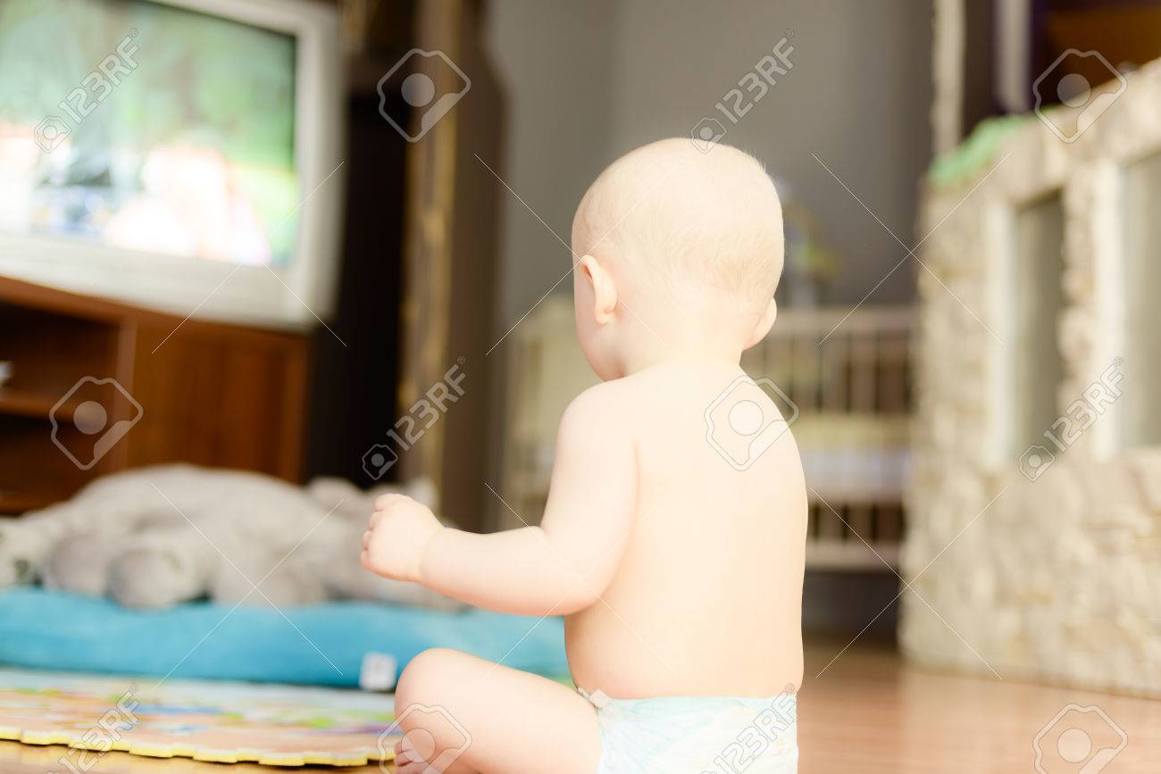赤ちゃんのおむつで床に座ってテレビを見て の写真素材 画像素材 Image