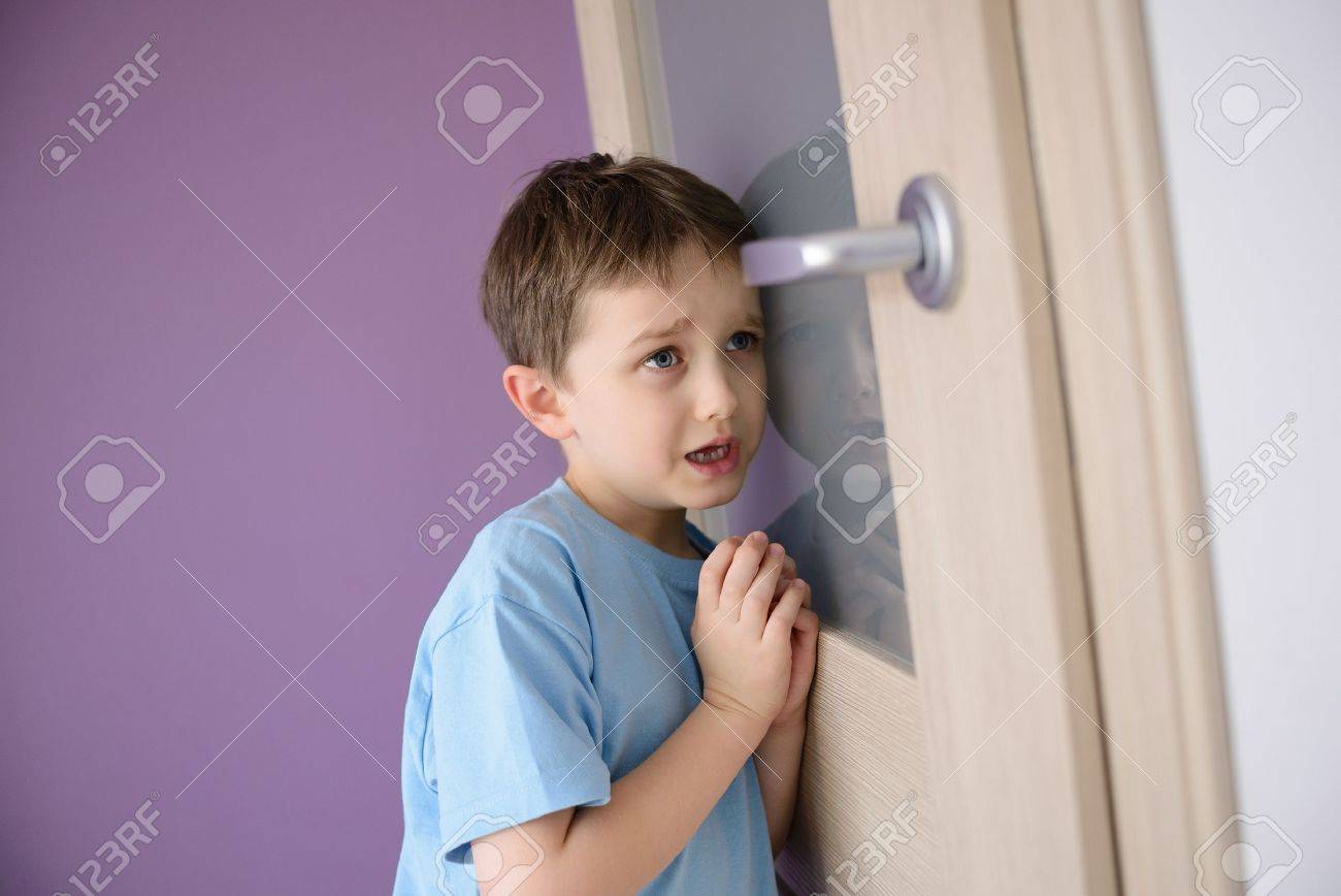 泣いて 彼の耳に押されたガラスのドアを通って話している親を聞いておびえた子供 の写真素材 画像素材 Image