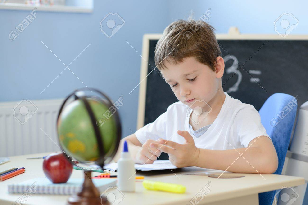 7 years old boy solves multiplication table in his copybook and counting on fingers. Back to school - 61918198 7 years old boy solves multiplication table in his copybook and counting on fingers. Back to school - 61918198