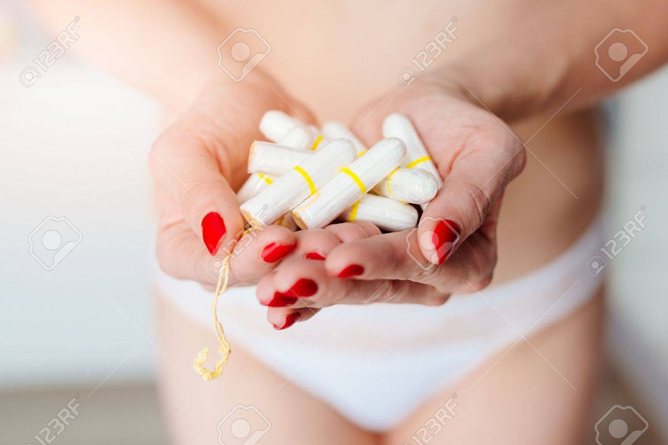 Close up on woman holding white cotton tampons in hand. Woman period - 74266592 Close up on woman holding white cotton tampons in hand. Woman period - 74266592