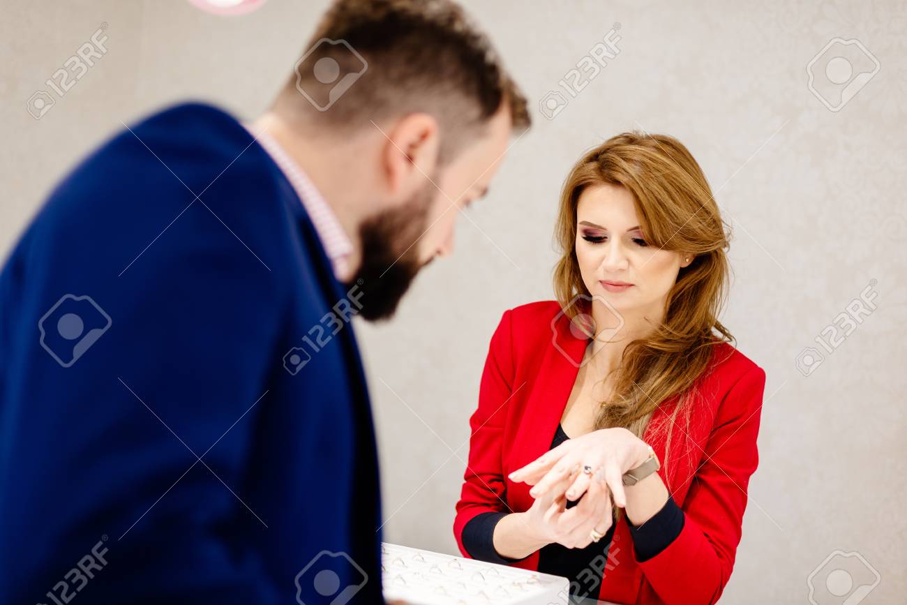 ジュエリーリングで婚約指輪を選ぶ男 高級宝飾店の女性売り手が指輪をプレゼント 婚約指輪を買ってる宝石店女性の宝石商 の写真素材 画像素材 Image