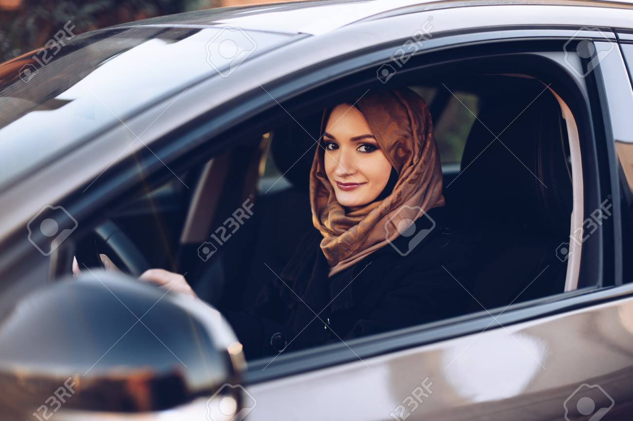 Young arabic woman in hijab driving a car - 114883487 Young arabic woman in hijab driving a car - 114883487