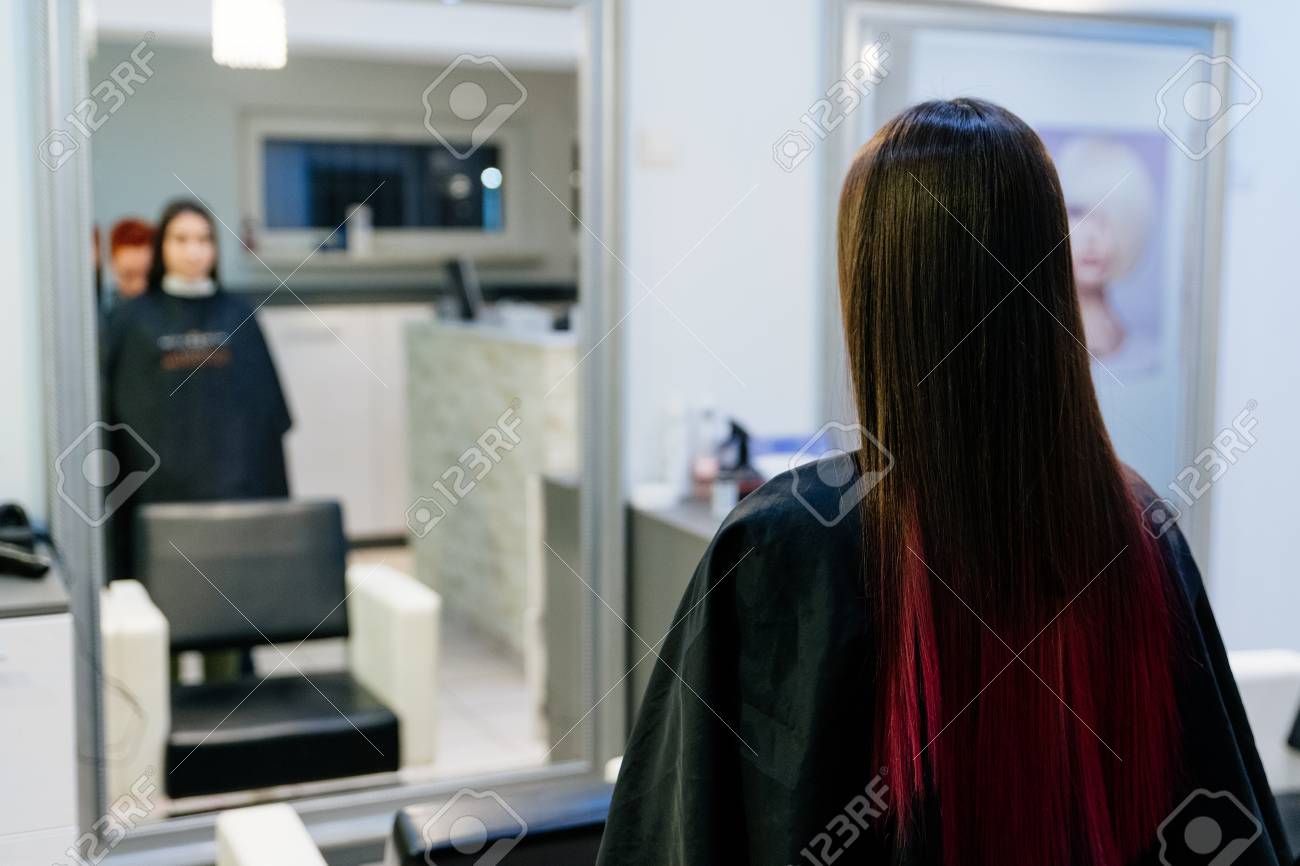 Cabeleireiro divide o cabelo feminino em seções com o pente segurando o  cabelo com as mãos em salão de cabeleireiro close-up.