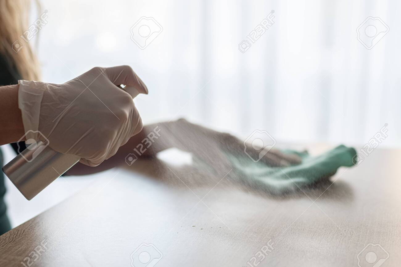 Woman disinfects table with spray disinfectant liquid - 142861719 Woman disinfects table with spray disinfectant liquid - 142861719
