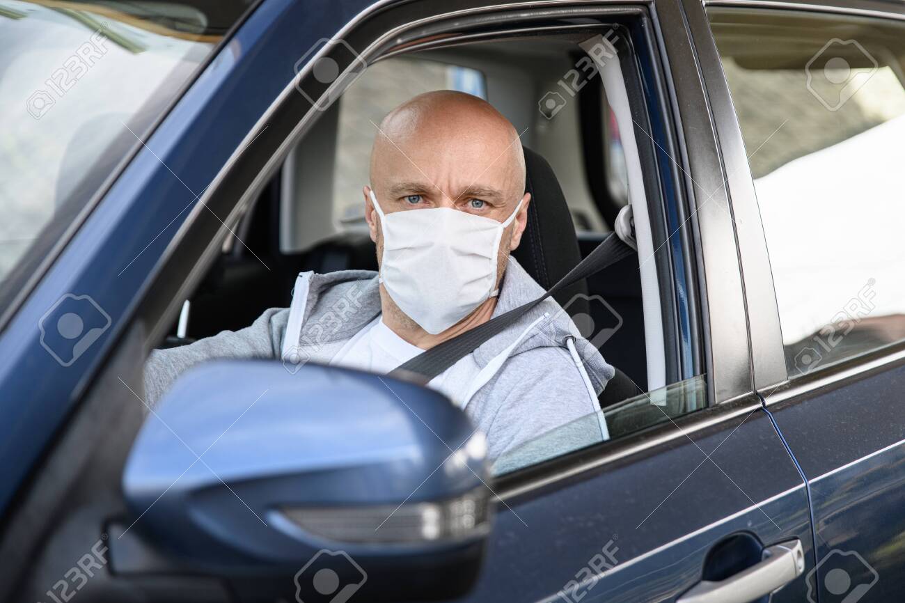 Man driving a car in medical protective mask. - 145297116 Man driving a car in medical protective mask. - 145297116