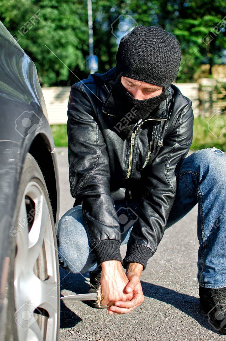 仮面の男は車のタイヤをを刺し傷 復讐の概念 の写真素材 画像素材 Image