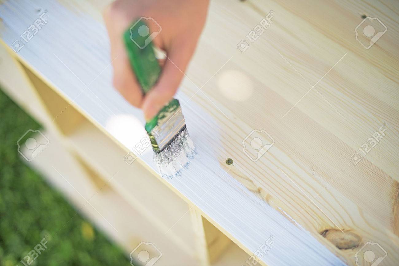 Female hand with brush painting wooden furniture. - 42186410 Female hand with brush painting wooden furniture. - 42186410