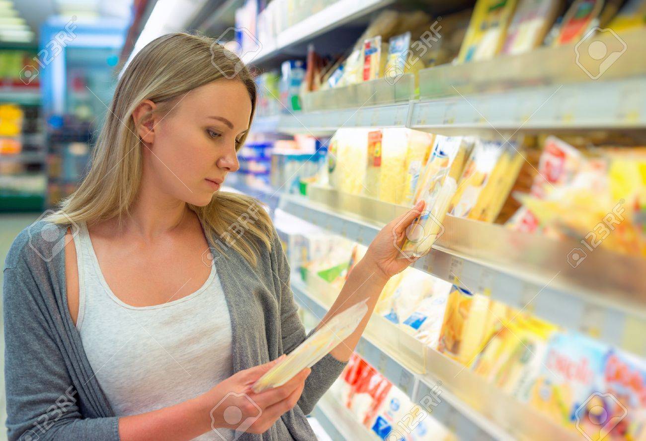 Woman choosing cheese in grocery store. - 48955327 Woman choosing cheese in grocery store. - 48955327