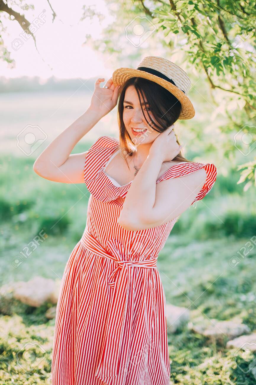 Beautiful Girl In A Hat And Red Dress Posing In Nature Sunset Stock Photo Picture And Royalty Free Image Image