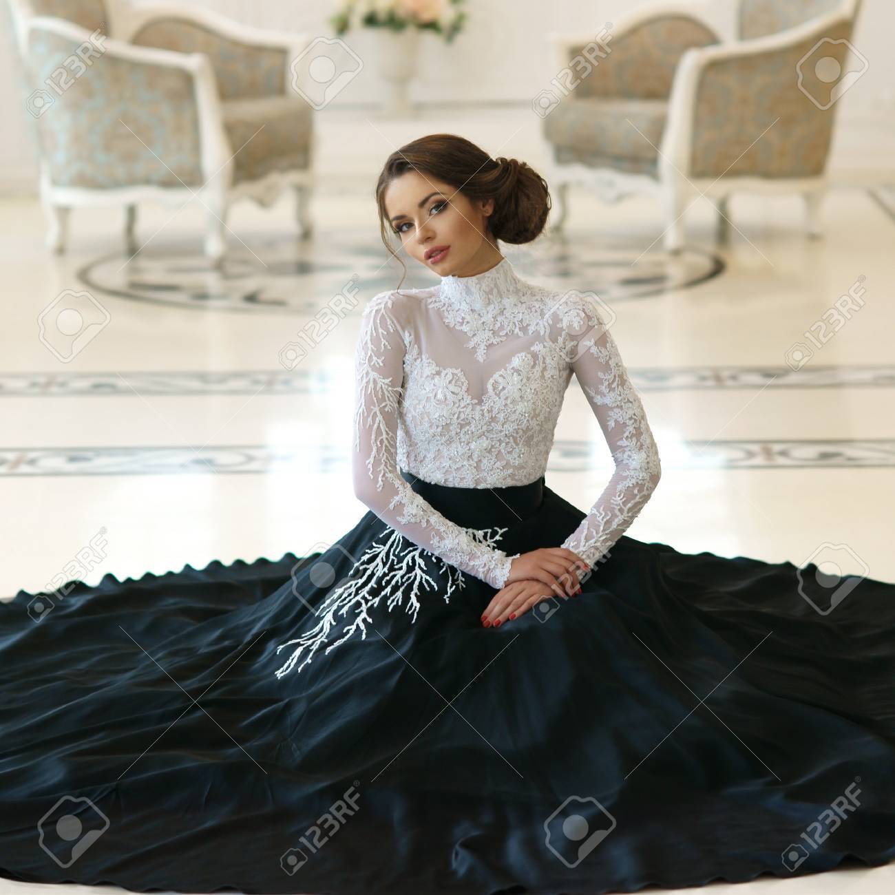 豪華なホワイト インテリアの床の上に座って高価なイブニング ドレスで美しいエレガントな女の子 の写真素材 画像素材 Image