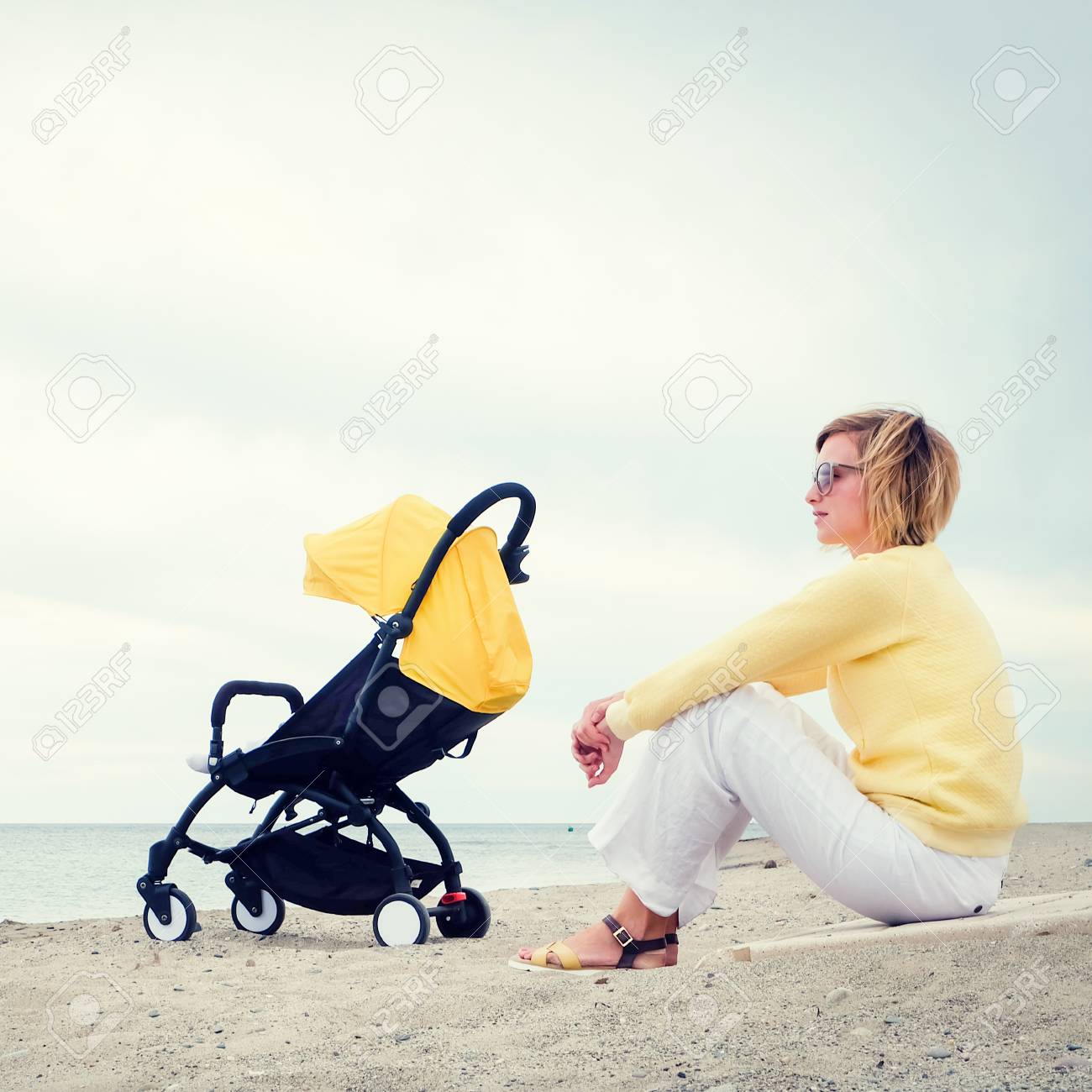 Jeune Femme Regardant A Travers La Mer Tout En Etant Assis Sur La Plage Avec Bebe Dort Dans La Poussette Banque D Images Et Photos Libres De Droits Image
