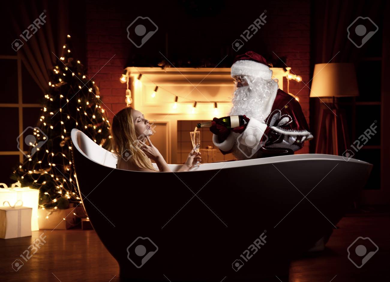 Young beautiful woman lying in bathtub over christmas tree interior background with retro light bulbs and santa claus pour champagne in glass. New year Holidays celebration concept - 90059255 Young beautiful woman lying in bathtub over christmas tree interior background with retro light bulbs and santa claus pour champagne in glass. New year Holidays celebration concept - 90059255