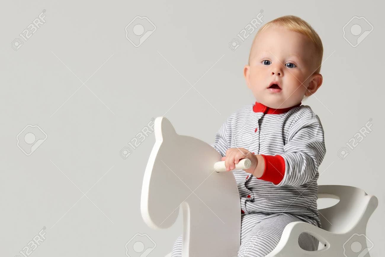 Infant Enfant Bebe Garcon Enfant Enfant Assis Balade Blanche Jouet Petit Cheval De Bois En Drap De Corps Rayures Rouges Regardant Le Coin Sur Fond Gris Banque D Images Et Photos Libres De