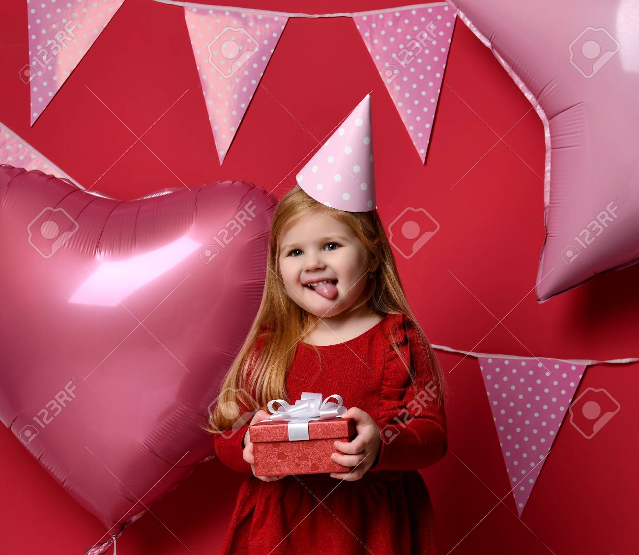 ピンクの風船と赤いプレゼントプレゼントと誕生日キャップ笑顔で愛らしいかわいい女の子 3歳の幼児の子供を祝う の写真素材 画像素材 Image