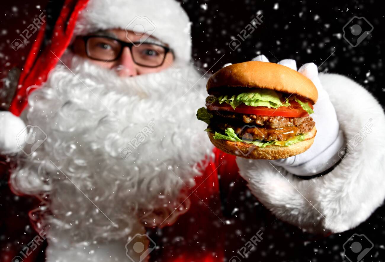 Happy Santa Claus hold tasty burger sandwich hamburger in hand closeup under snow. New year and Merry Christmas fast food concept - 135952641 Happy Santa Claus hold tasty burger sandwich hamburger in hand closeup under snow. New year and Merry Christmas fast food concept - 135952641