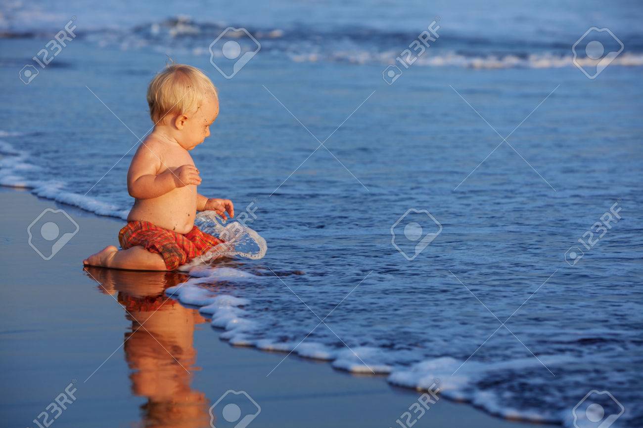 Le Coucher De Soleil Plage Bebe Heureux Nageur Assis Sur Le Sable Noir Et Regarder Surfer Sur La Mer Avec De La Mousse Et Les Projections Pour Nager Dans Les Vagues Famille