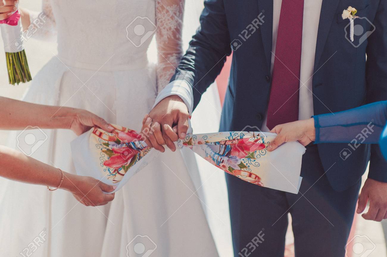 Hände der braut und des bräutigams gebundene hochzeitstücher. der priester bindet das handtuch der braut. hände junger paare in der kirche. paar händchen haltend handtuch in der kirche zeremonie. hochzeitstag. - 82728537 Hände der braut und des bräutigams gebundene hochzeitstücher. der priester bindet das handtuch der braut. hände junger paare in der kirche. paar händchen haltend handtuch in der kirche zeremonie. hochzeitstag. - 82728537