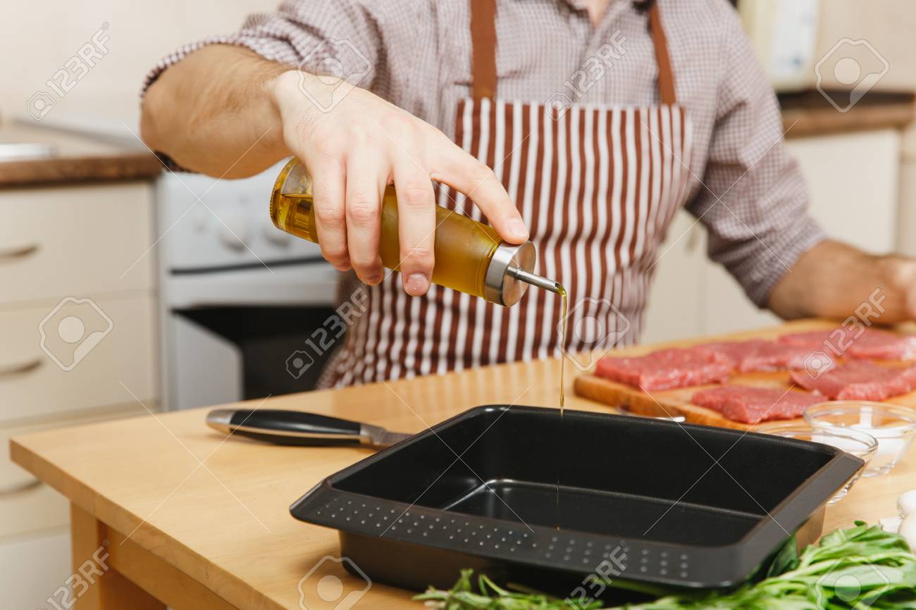 Close Up Man In Apron Sitting At Table Pouring Olive Oil In
