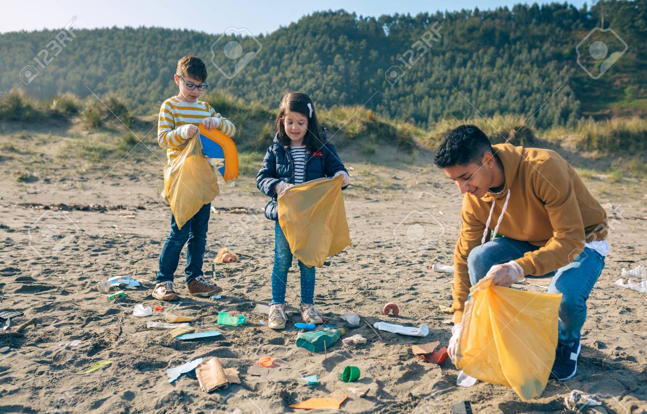 Group of young volunteers picking up trash on the beach - 123928218 Group of young volunteers picking up trash on the beach - 123928218
