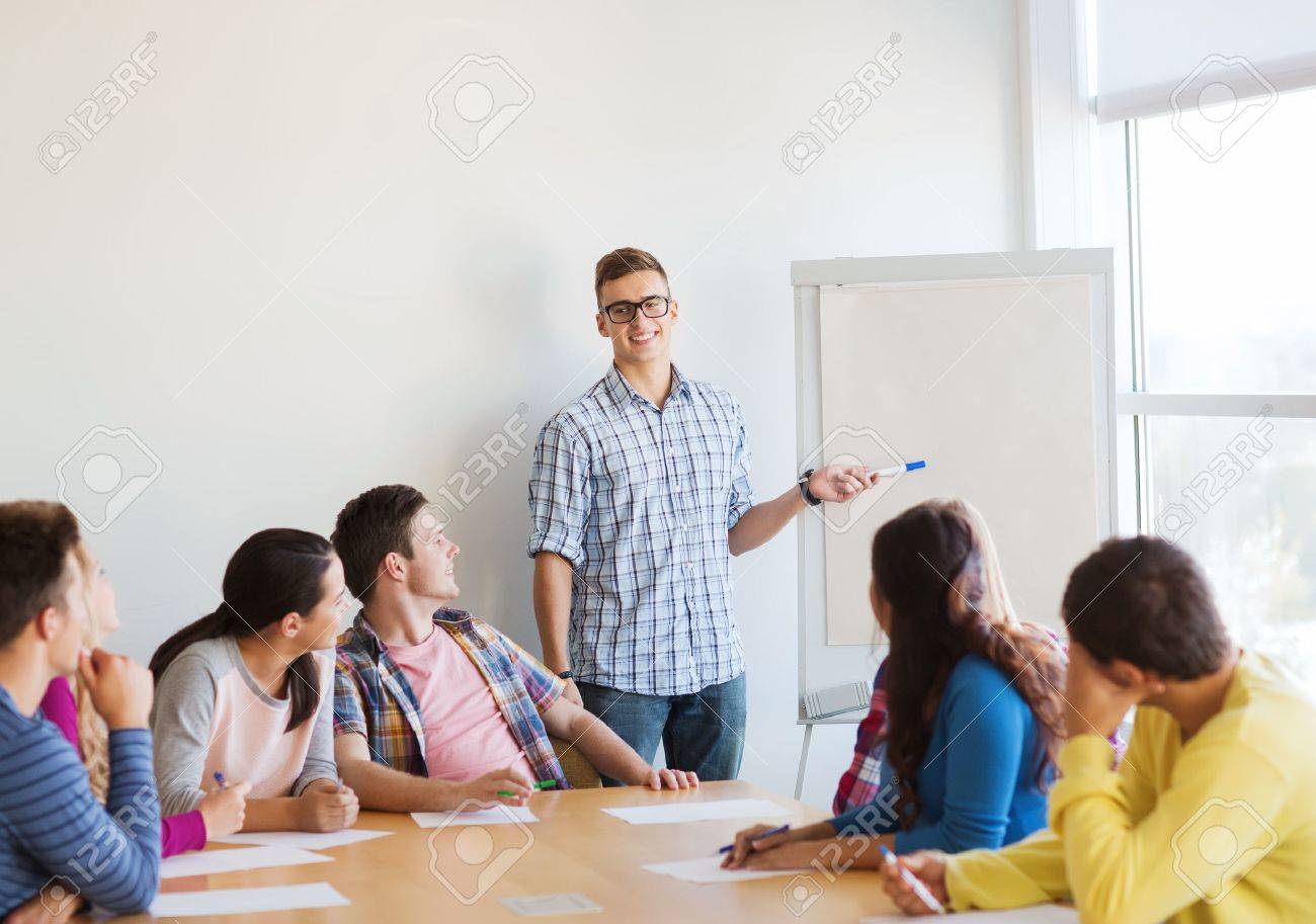 education, teamwork and people concept - smiling students with white board sitting an table indoors - 32578298 education, teamwork and people concept - smiling students with white board sitting an table indoors - 32578298