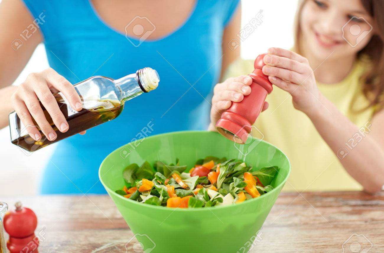 food, healthy eating, family and people concept - close up of happy girl and mother cooking salad for dinner and adding spices in kitchen - 37682533 food, healthy eating, family and people concept - close up of happy girl and mother cooking salad for dinner and adding spices in kitchen - 37682533