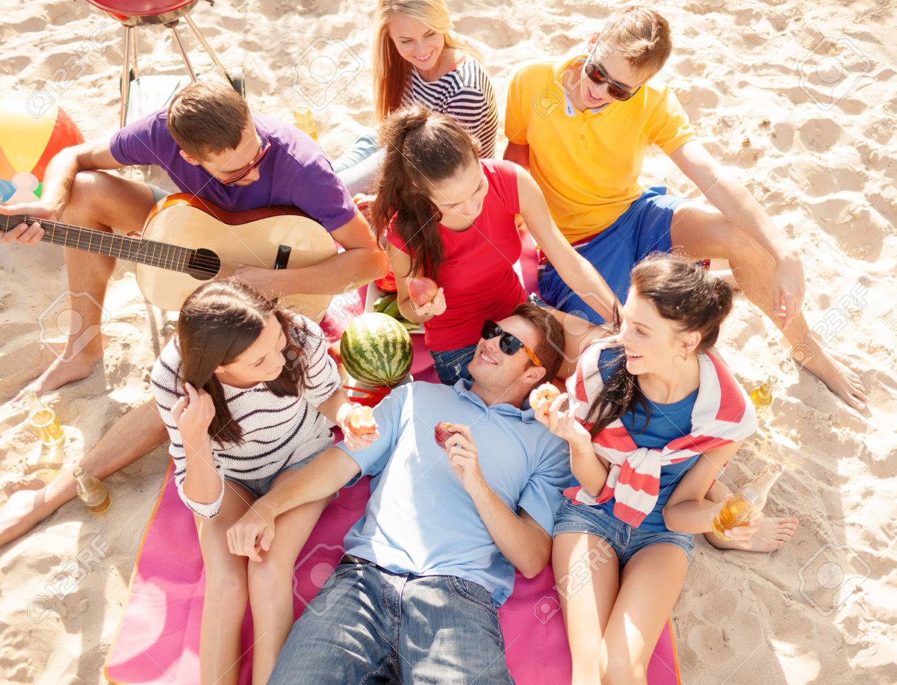 summer holidays, vacation, music, happy people concept - group of happy friends having picnic and playing guitar on beach - 40250554 summer holidays, vacation, music, happy people concept - group of happy friends having picnic and playing guitar on beach - 40250554