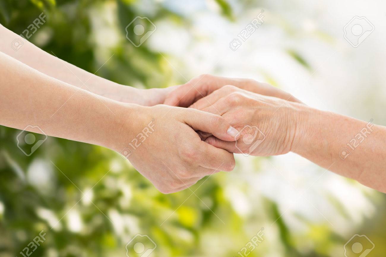 people, age, family, care and support concept - close up of senior woman and young woman holding hands over green natural background - 48511436 people, age, family, care and support concept - close up of senior woman and young woman holding hands over green natural background - 48511436
