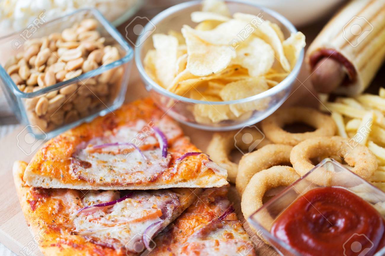 ファーストフードや不健康な食事の概念 は ピザ 揚げイカリング ポテトチップス ピーナッツ 木製テーブル トップ ビューでケチャップのクローズ アップ の写真素材 画像素材 Image